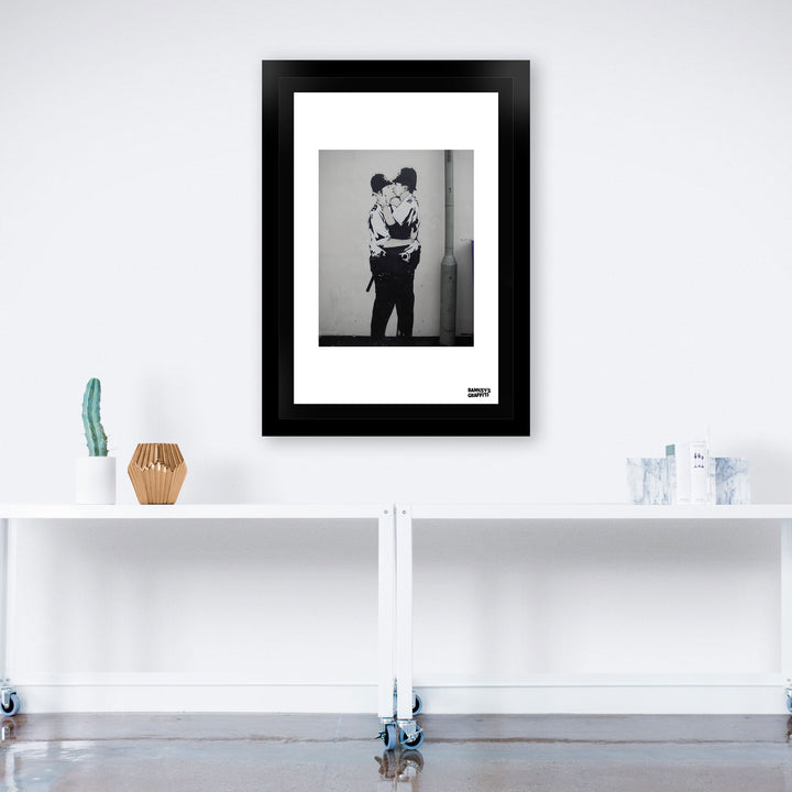 Kissing Coppers, a framed print of Banksy's Graffiti-Homekor Mounted in a work room