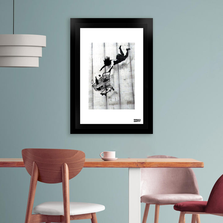 Shop till you Drop, a framed print of Banksy's Graffiti-Homekor Mounted in a cozy room